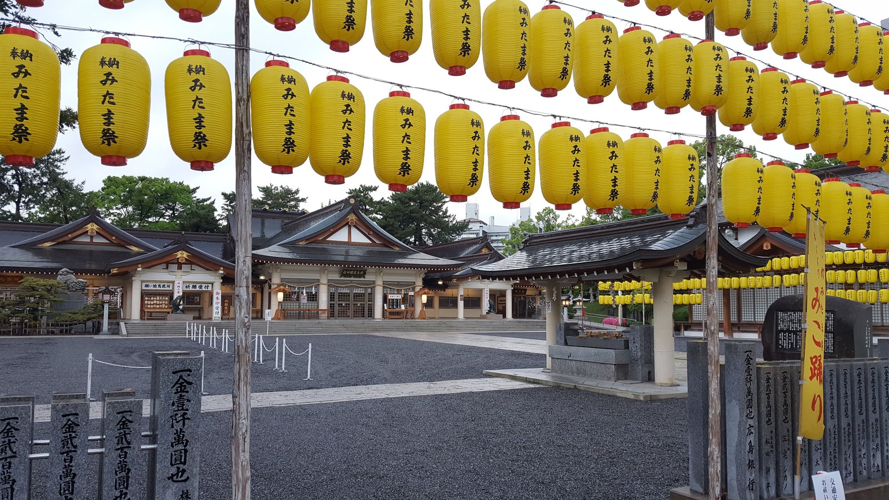 Hundreds of yellow lanterns hanging at the entrance of a Japanese shrine.