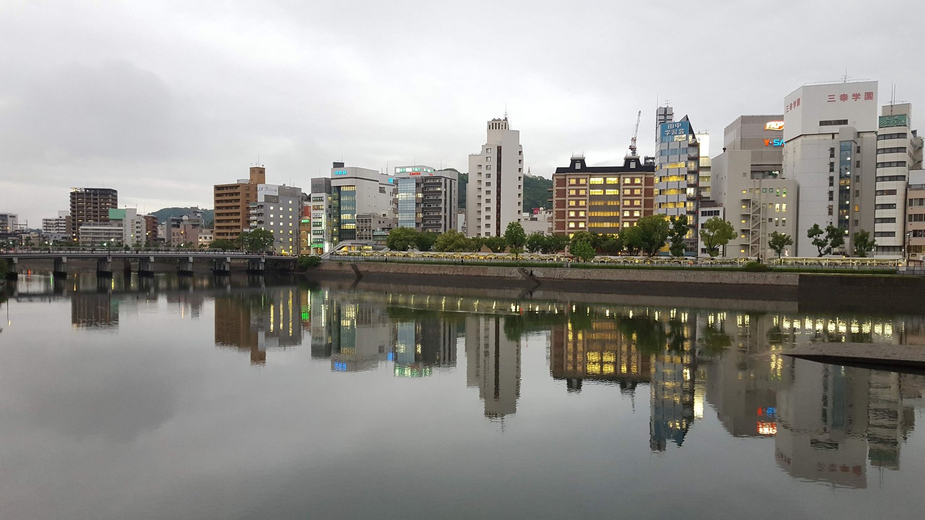 Modern buildings along the waterfront reflect in the water below.
