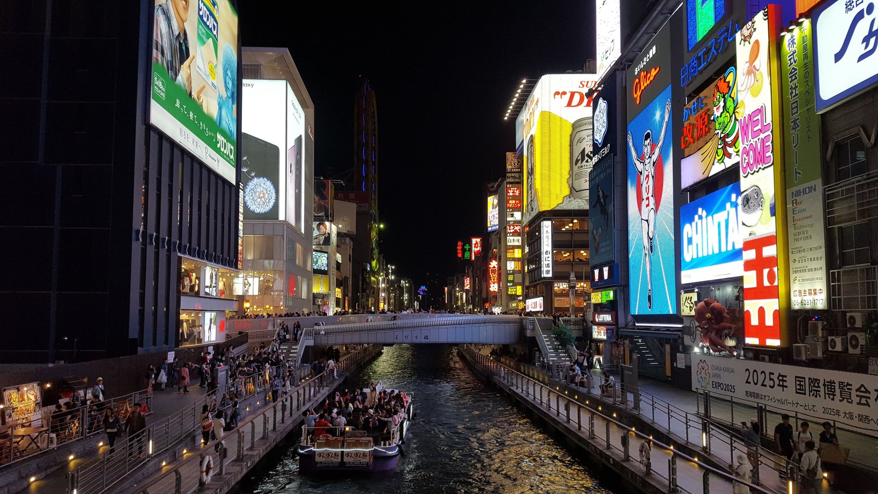 Light displays on shops illuminate the water below.
