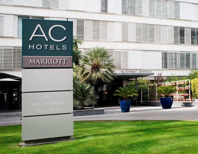 Exterior of AC Hotels by Marriott with a sign reading 'AC Victoria Suites' and landscaped entrance.