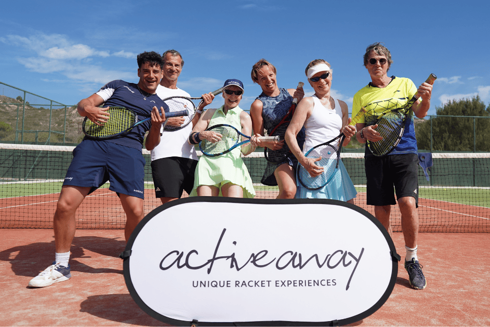 Six diverse tennis players smiling with rackets on a clay court, standing behind an 'active away' banner.