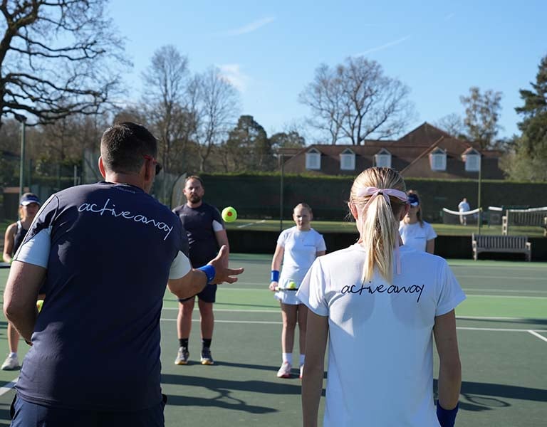 Junior tennis camp at Royal Russell School with Active Away coaches instructing children on tennis techniques on an outdoor court.