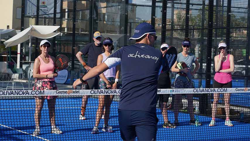 Group of people on a blue padel tennis court, guided by an instructor from Active Away, participating in a holiday activity session.