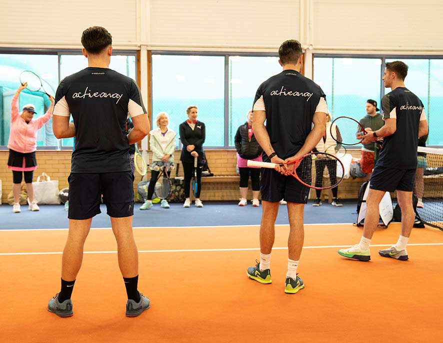 Tennis coaches leading a session at Active Away UK's indoor clinic, with participants and equipment visible.
