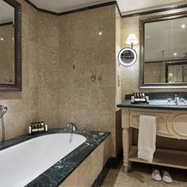 Luxury bathroom at Aphrodite Hills with marble bathtub, ornate mirror, and vanity.