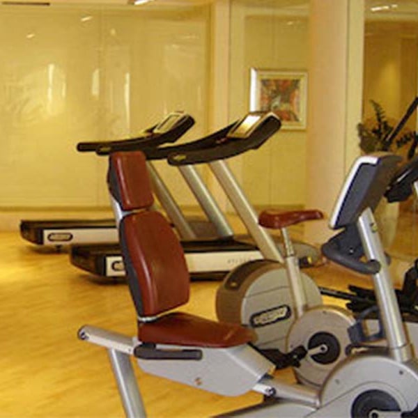 Interior of Aphrodite Hills Gym featuring treadmills and stationary bikes on a wooden floor with soft lighting.