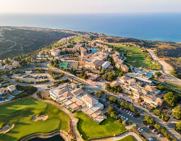 Aerial view of Aphrodite Hills Resort in Cyprus with golf course and Mediterranean Sea in the background.