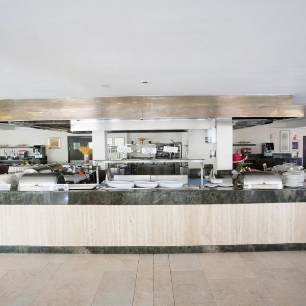 Buffet area in a beach club with a marble counter, stainless steel hood, and well-organised kitchen in the background.