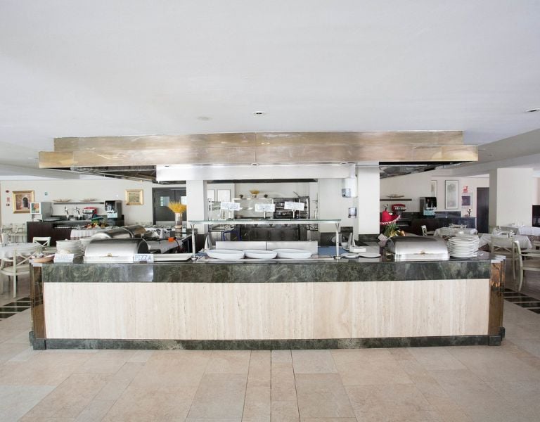 Buffet area in a beach club with a marble counter, stainless steel hood, and well-organised kitchen in the background.