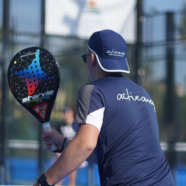 Padel coach holding a StarVie racket on an outdoor court with a blue activewear uniform.