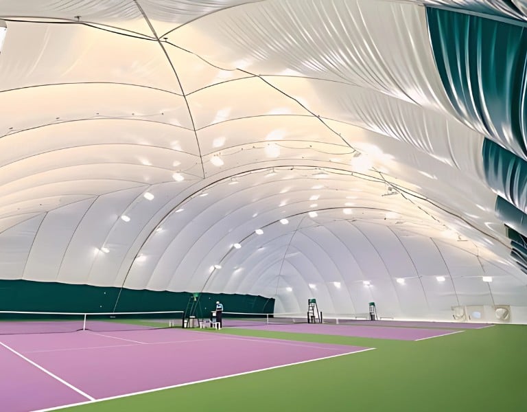 Indoor tennis court at DL Woking with a large inflated dome ceiling and green and purple flooring.