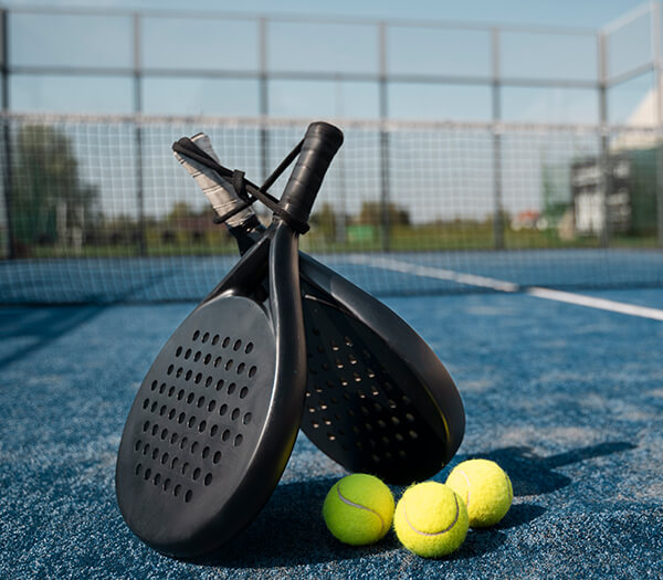 Padel rackets and tennis balls on a blue court at Dom Pedro Vilamoura, Portugal.