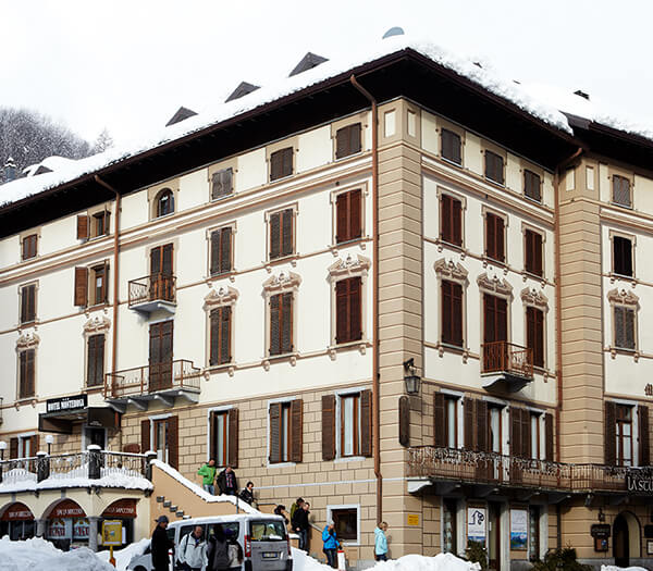 Exterior view of Hotel Monterosa, featuring a snow-covered classic alpine building with guests arriving.