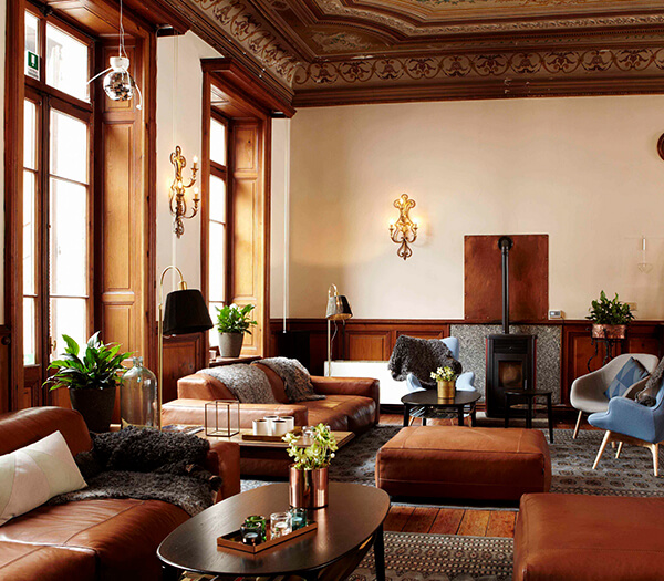 Hotel Monterosa lounge with vintage wood panelling, leather sofas, armchairs, coffee table, and green plants.