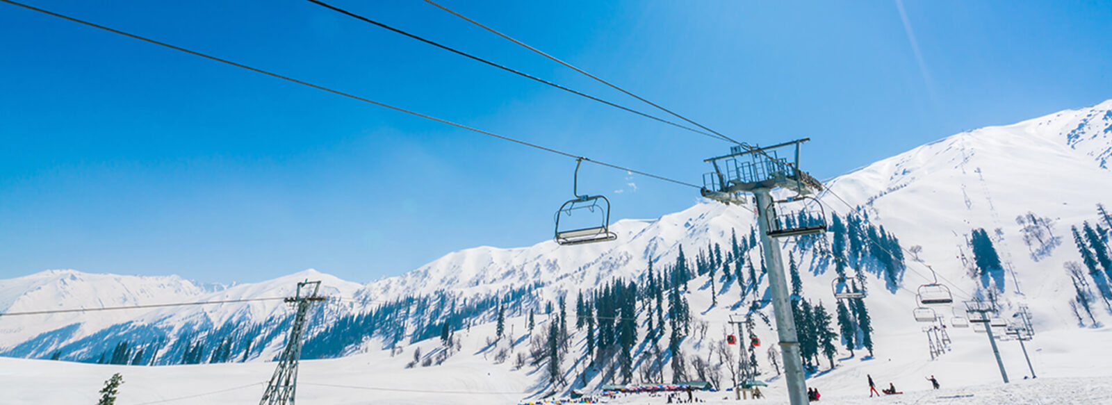 Ski lifts and snow-covered mountains with pine trees at Hotel Monterosa, under a clear blue sky.