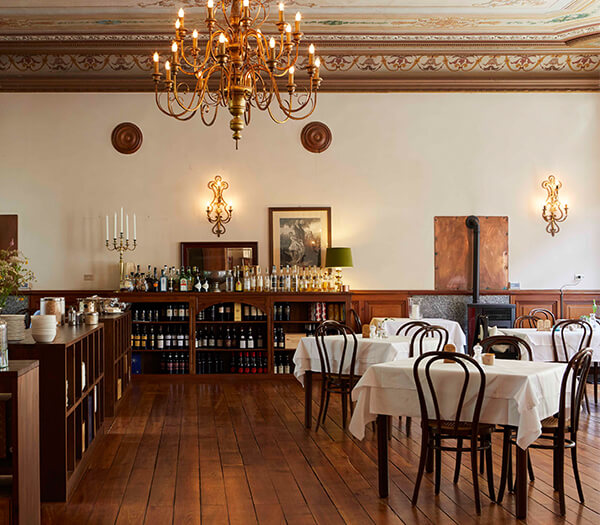 Elegant dining room at Hotel Monterosa Restaurant with wooden floors, vintage chairs, and an ornate chandelier.