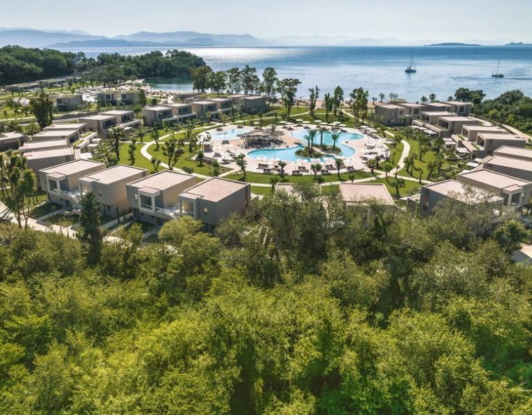 Aerial view of Ikos Odisia resort featuring a circular layout with central pool, lush greenery, and coastal surroundings.