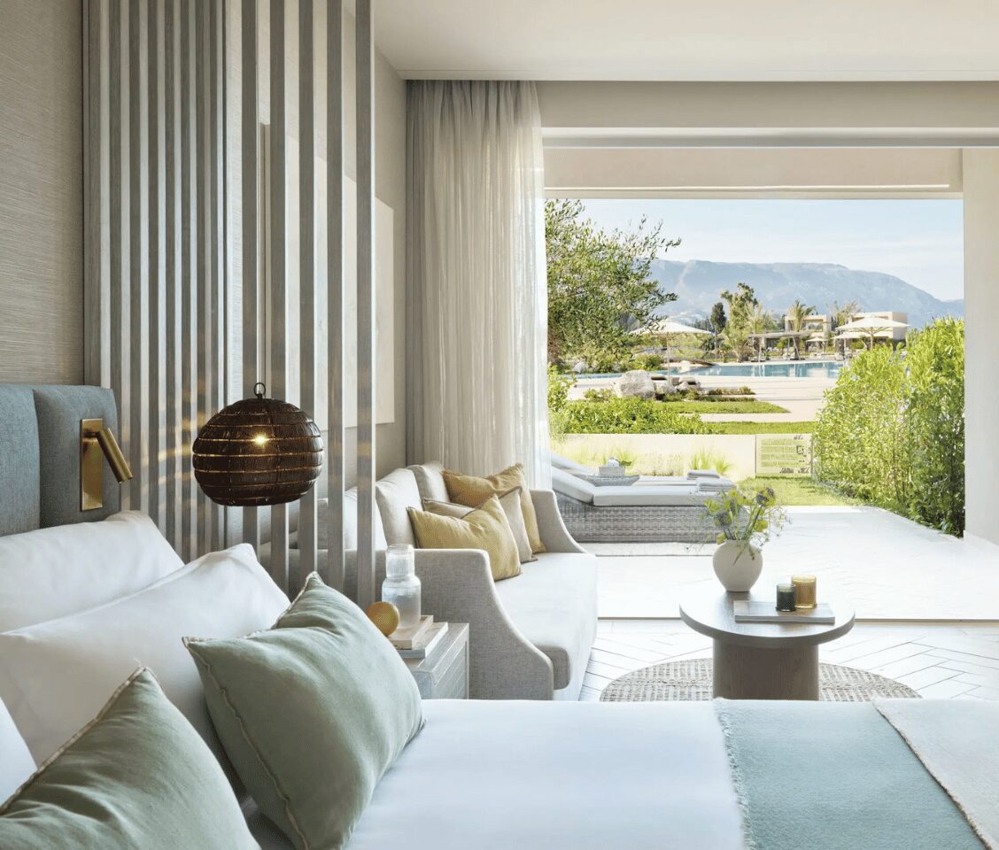 Ikos Odisia Junior Bungalow Suite interior with open-plan design, featuring access to a private garden and pool view.