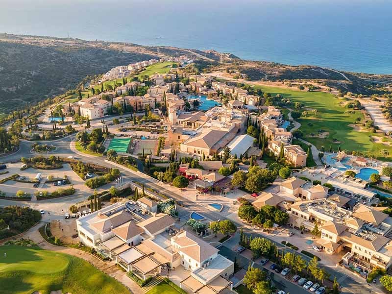 Aerial view of Aphrodite Hills resort in Cyprus, featuring villas, leisure facilities, and the Mediterranean Sea in the background.