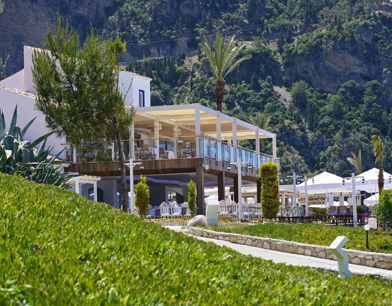 Outdoor restaurant at Liberty Lykia Family resort with scenic mountain views and lush greenery.