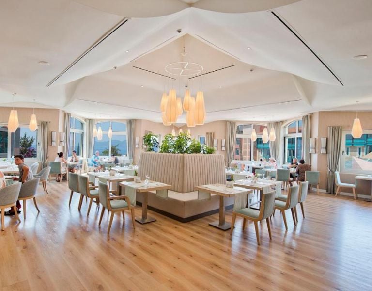 Spacious interior of Liberty Lykia's Center Restaurant with modern white decor, pendant lights, and large windows.