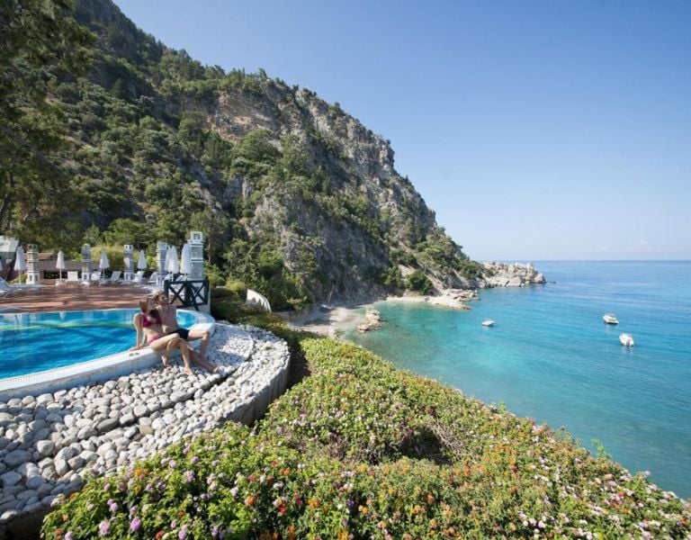 View from Liberty Lykia pool overlooking turquoise Mediterranean Sea and lush cliffs.