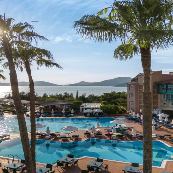Outdoor pool area at Liberty Sentido Hotel with sun loungers, palm trees, and a sea view in the background.