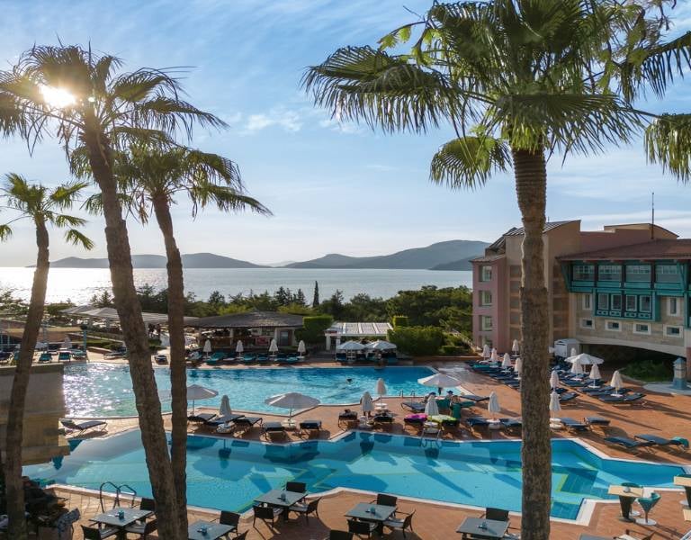 Outdoor pool area at Liberty Sentido Hotel with sun loungers, palm trees, and a sea view in the background.
