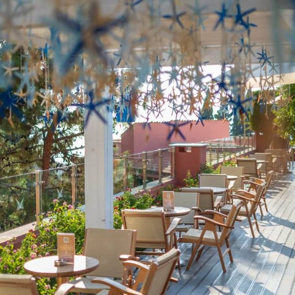Outdoor terrace at Liberty Sentido Gallery Restaurant with wooden chairs, green plants, and star decorations.