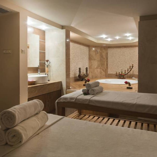 Serene spa room at Liberty Sentido Gallery with massage tables, fresh towels, and a jacuzzi surrounded by rose petals.