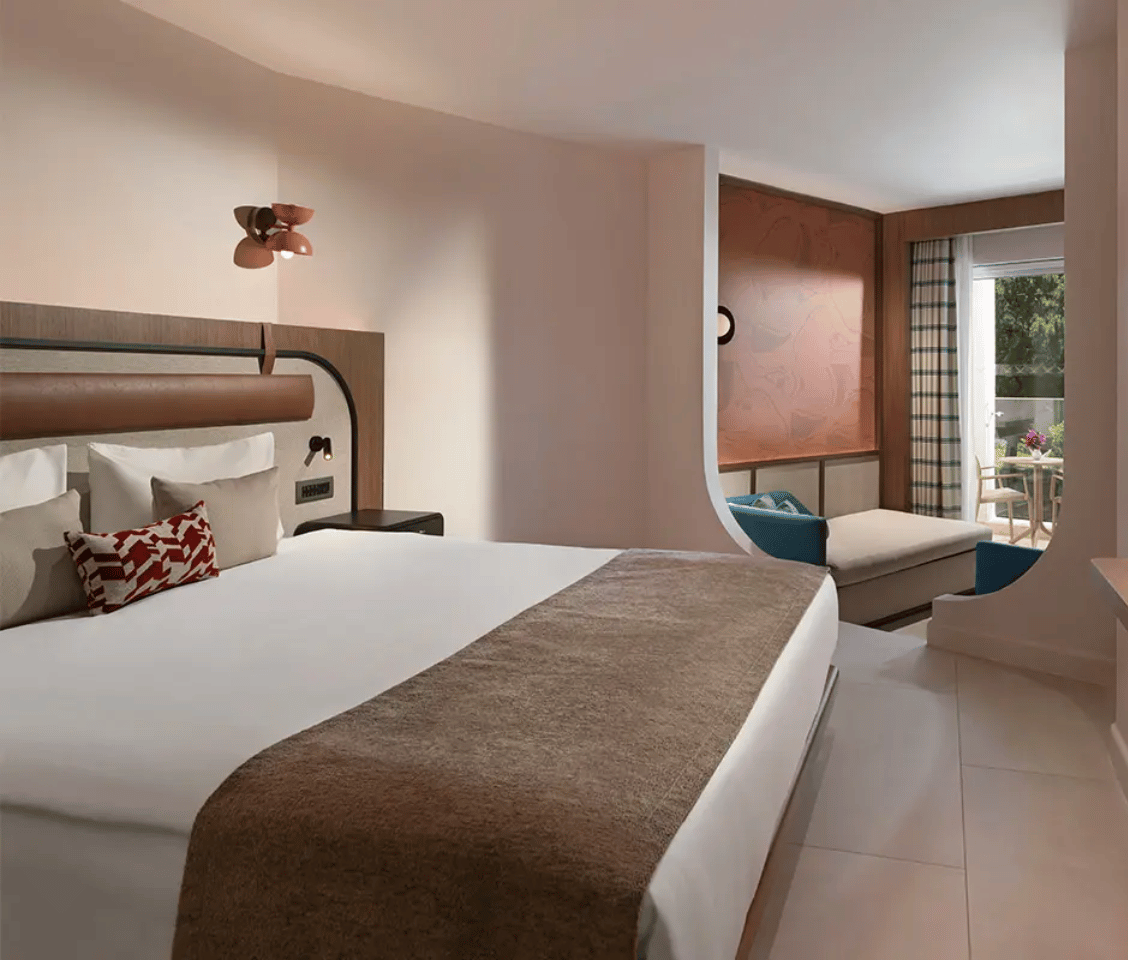 Deluxe room at Liberty Village with a large bed, elegant decor, and a seating area overlooking greenery.