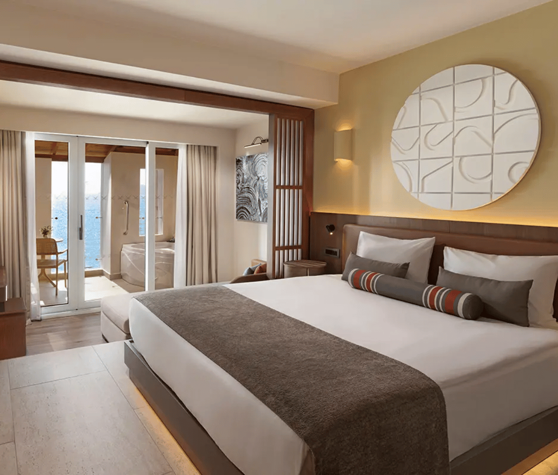Luxurious hotel room at Liberty Village with a king-sized bed, balcony with sea view, and private jacuzzi.