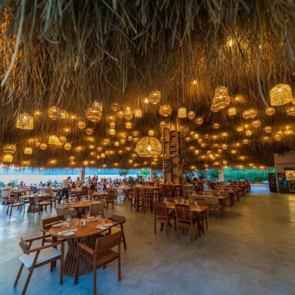 Liberty Village restaurant with rattan light fixtures hanging from the ceiling and wooden dining furniture creating a cosy, open-air ambiance.