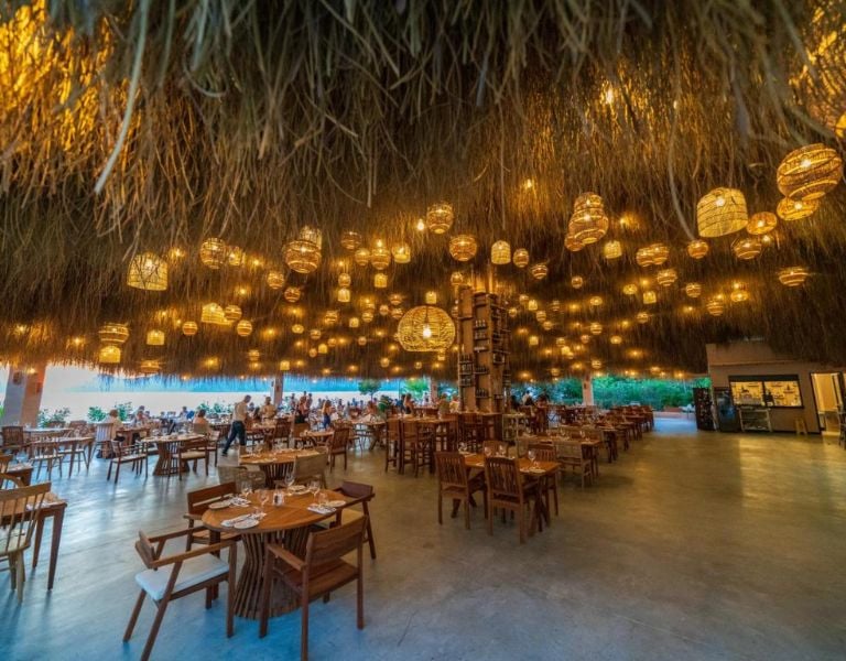 Liberty Village restaurant with rattan light fixtures hanging from the ceiling and wooden dining furniture creating a cosy, open-air ambiance.