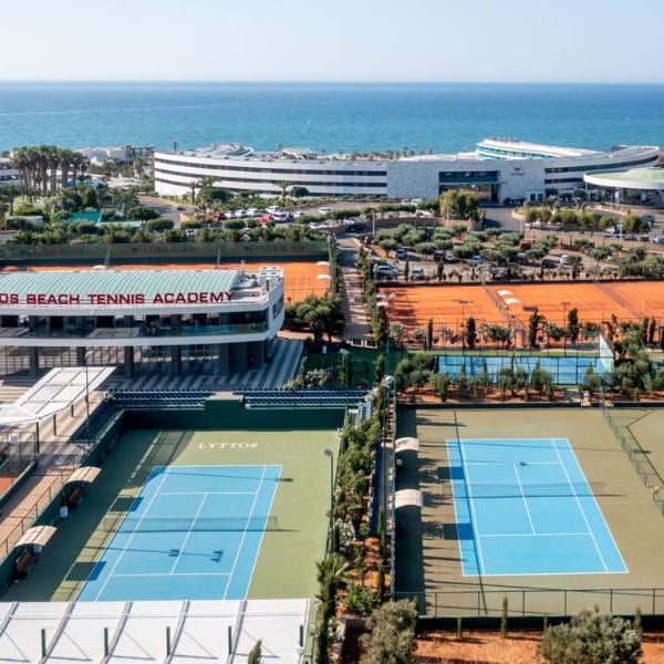 Aerial view of Lyttos Beach Tennis Academy with clay and hard courts near the Mediterranean Sea.