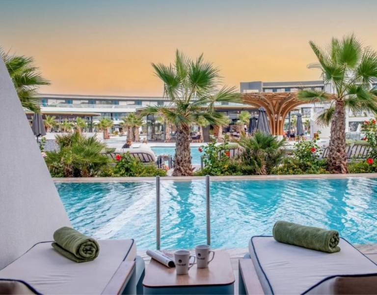 Lyttos Gallery private pool view with sun loungers, palm trees, and a modern architectural backdrop.
