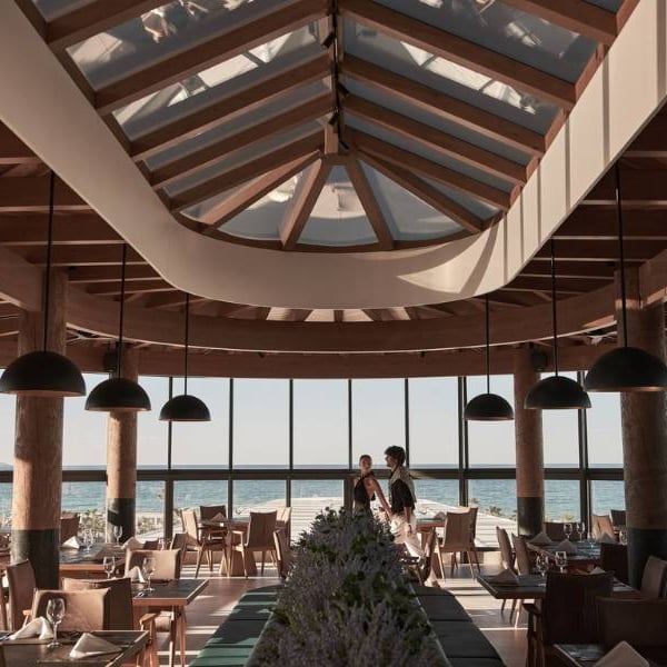 Interior of Lyttos Gallery Restaurant with wooden beams, pendant lights, and sea-view windows.