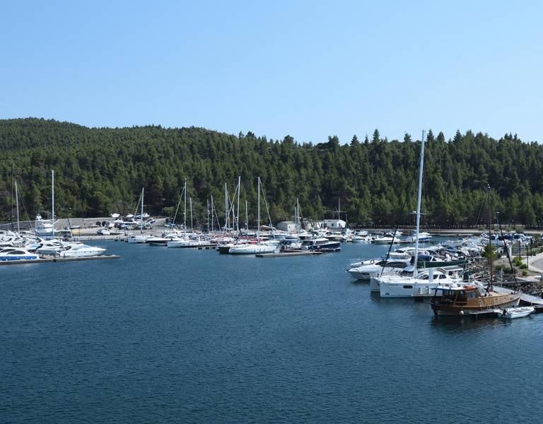 Yachts and boats docked at Meliton Gallery marina, surrounded by green hills and blue waters.
