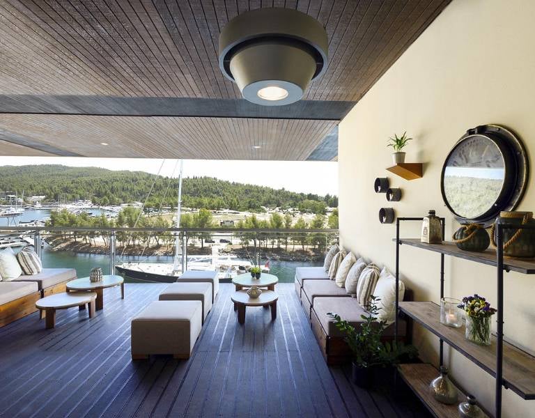 Outdoor deck at Meliton Gallery with lounge furniture, marina view, and green hills in the background.