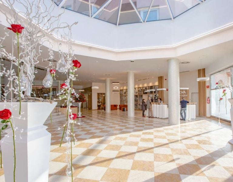 Lobby of Oliva Nova Padel Gallery with elegant floor tiles, modern decor, and floral arrangements with red roses.