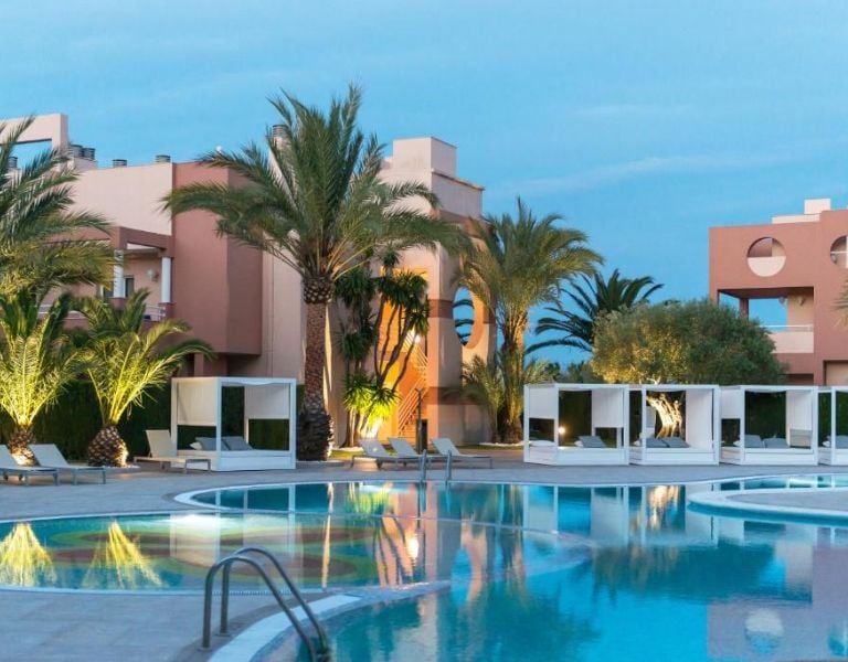Outdoor pool area at Oliva Nova Resort with modern cabanas and palm trees, offering a relaxing atmosphere.