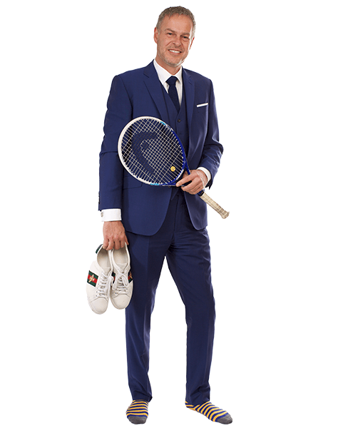 Peter Jones in a blue suit, holding a tennis racket and white trainers, with mismatched striped socks.