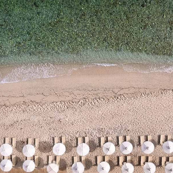 Aerial view of Royal Mare Beach featuring rows of sun loungers and white parasols, next to the turquoise sea.
