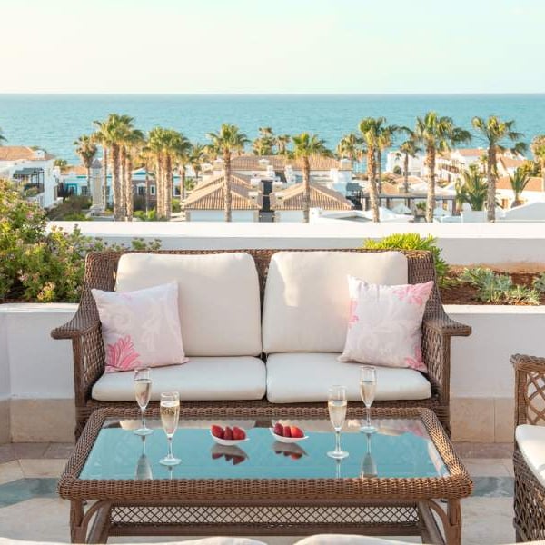 Terrace with wicker furniture, champagne glasses, and view of the sea at Royal Mare Gallery.
