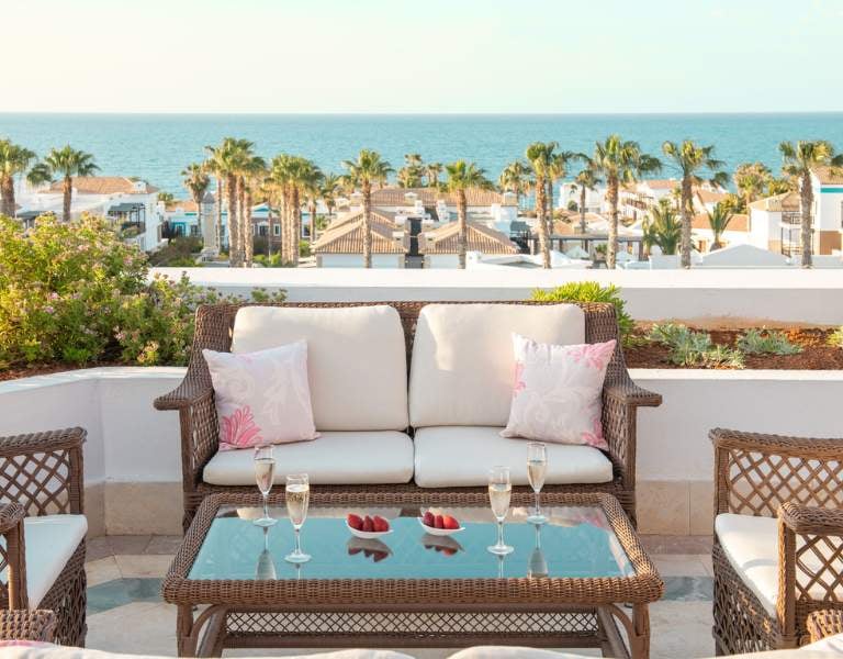 Terrace with wicker furniture, champagne glasses, and view of the sea at Royal Mare Gallery.
