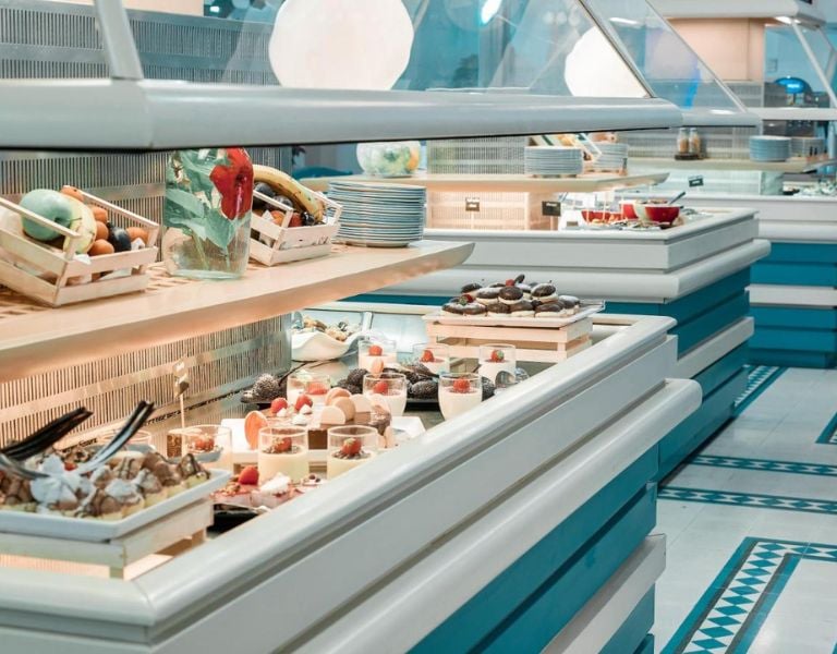 Royal Mare Gallery buffet with fresh fruits in baskets and trays of assorted desserts like pastries and cakes.