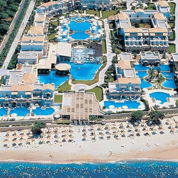 Aerial view of Aldemar Royal Mare resort in Crete, featuring multiple swimming pools, accommodation buildings, and a beachfront with loungers.