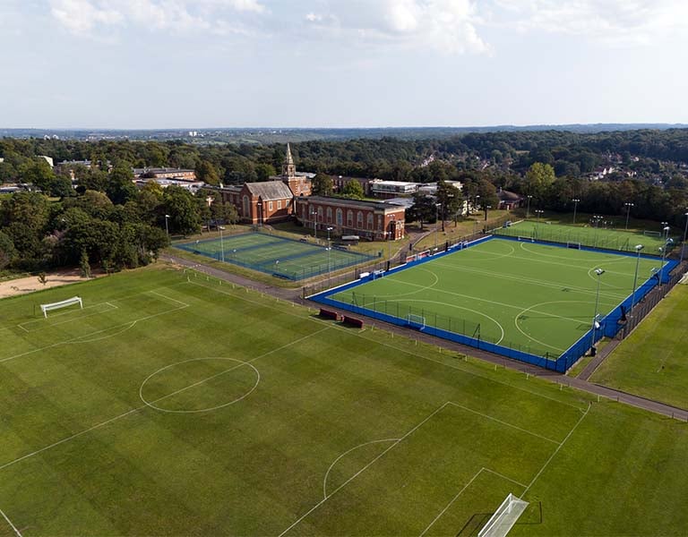 Aerial view of Royal Russell School with football pitches and tennis courts surrounded by greenery.