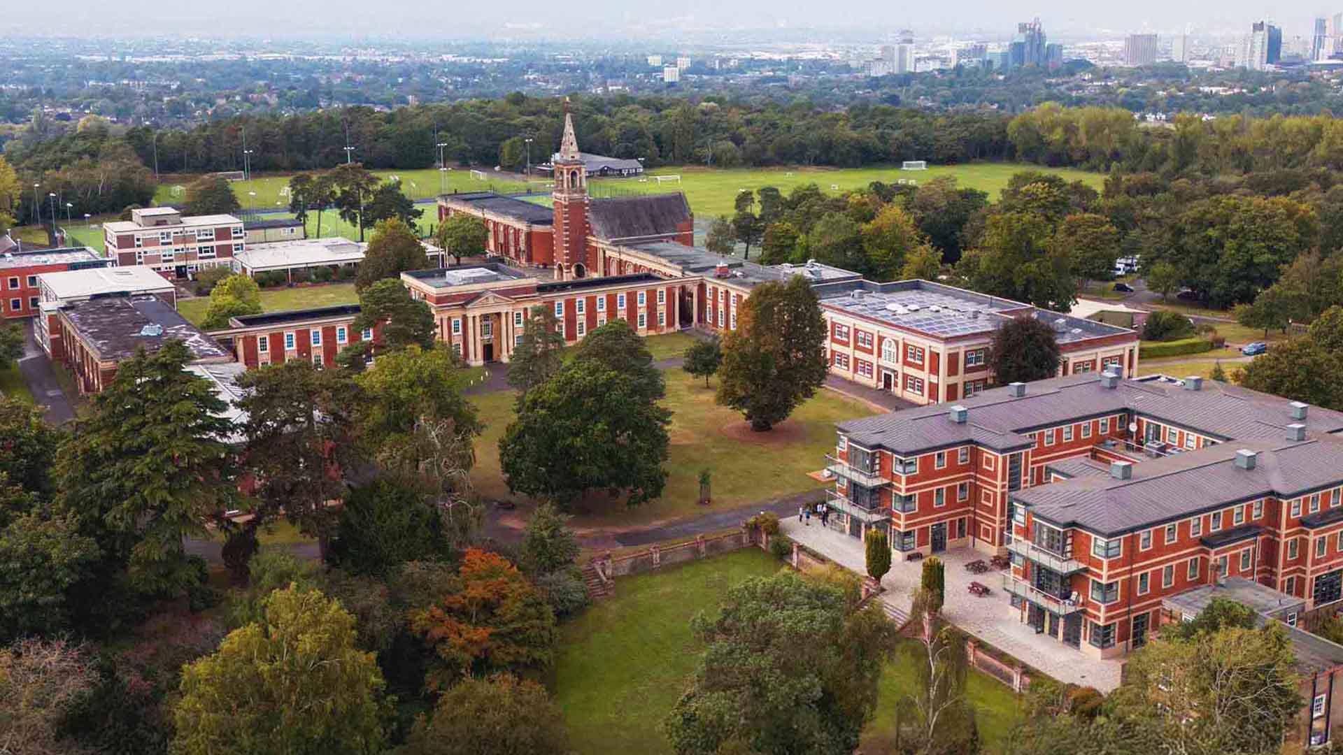 Aerial view of the Royal Russell School campus, featuring brick buildings and abundant greenery on a sunny day.