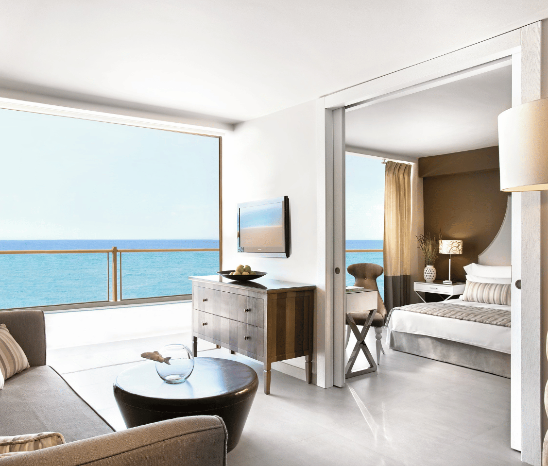 One-bedroom family suite at Sani Beach with modern furnishings and a sea view from a large window.
